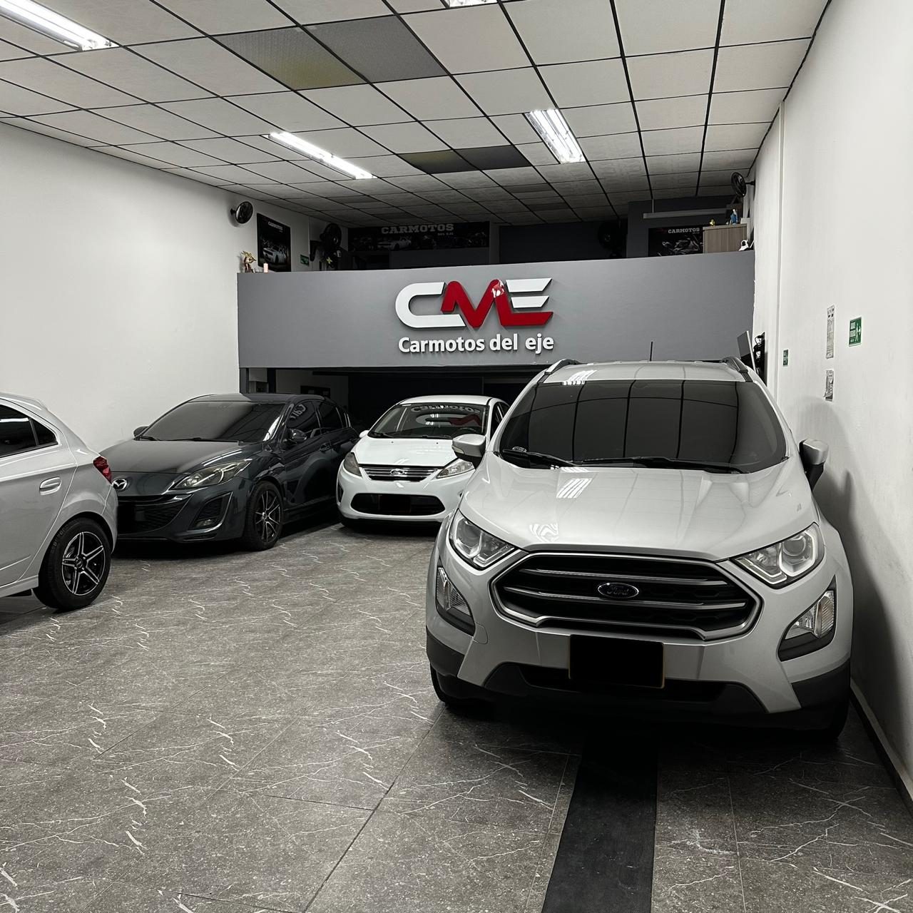 Interior del patio de Carmotos del Eje en Pereira, con el letrero CME y vehículos exhibidos